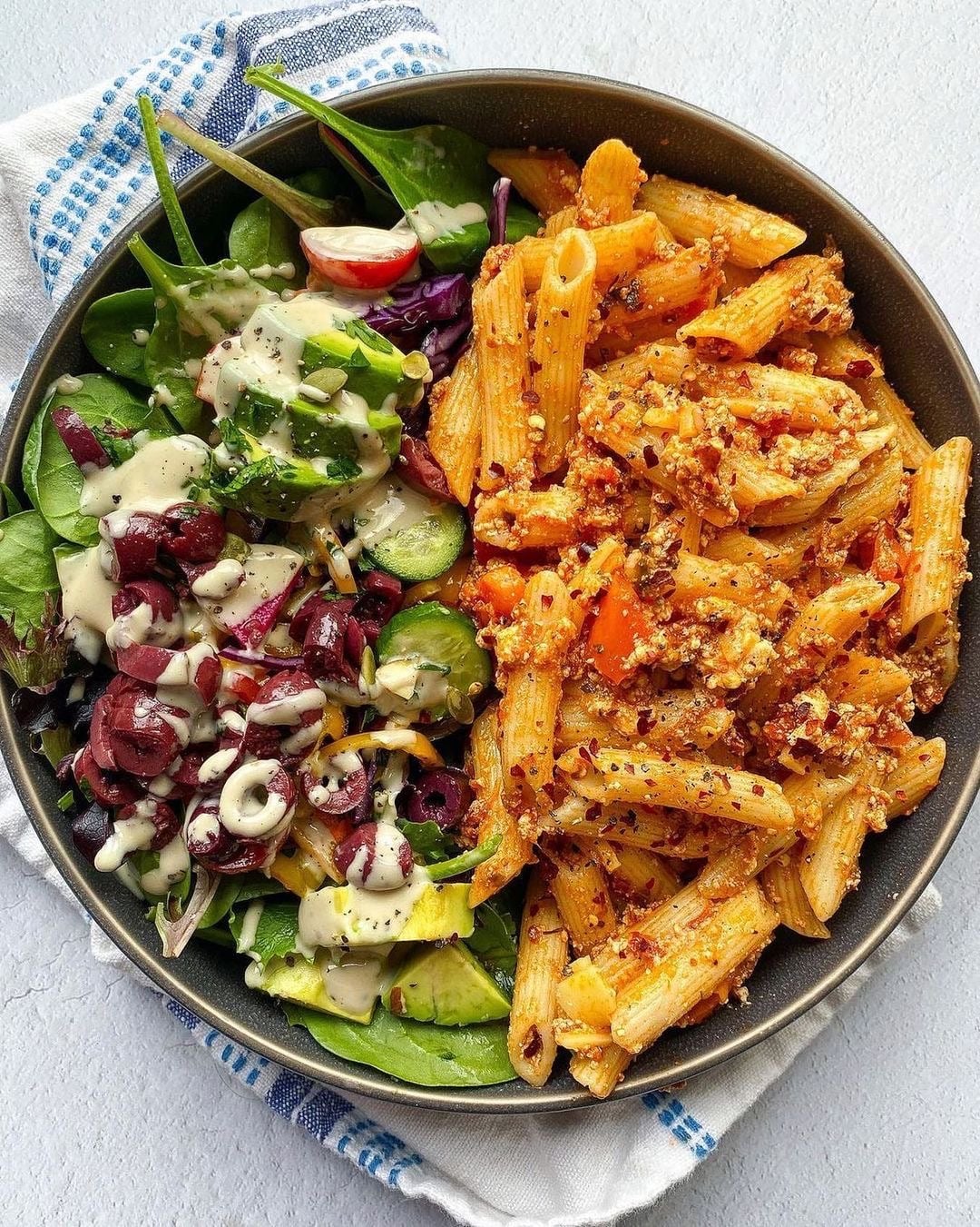 overhead view of a dinner plate with vegan baked ziti next to a green salad.