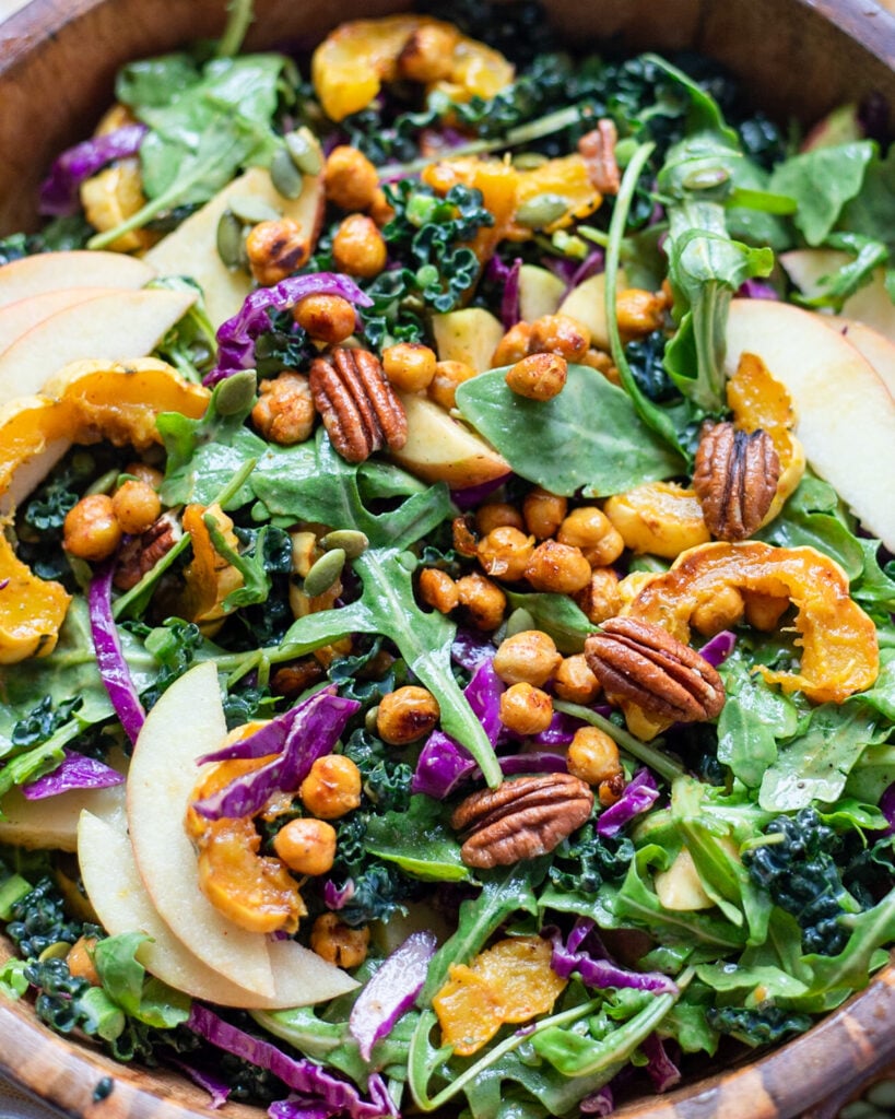 Close up view of Autumn Kale salad in a bowl with delicata squash, crispy chickpeas and apples