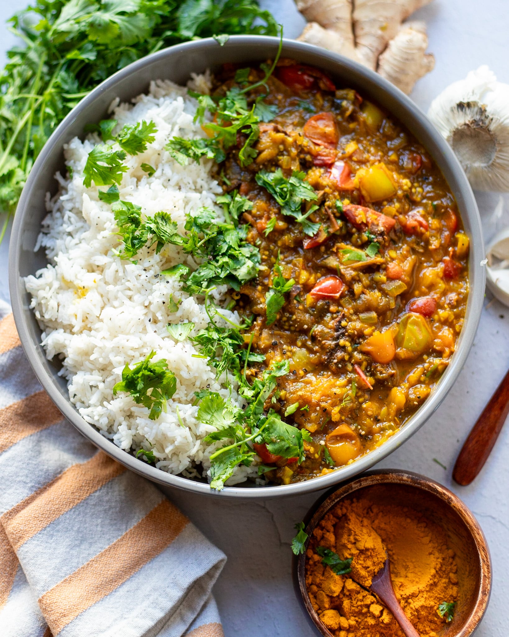 overhead view of a bowl with vegan baingan bharta curry with rice and cilantro.