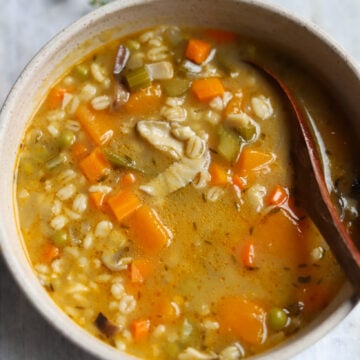 Close up of a large bowl of vegan mushroom barley soup with vegetables