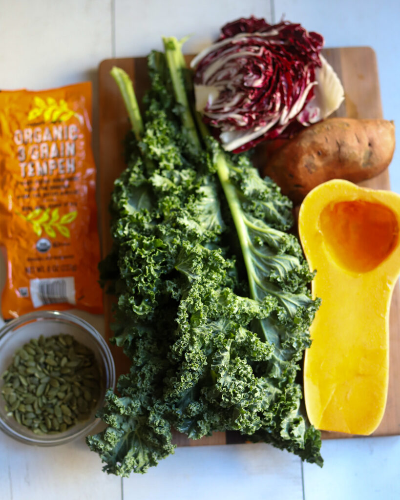 overhead view of ingredients for vegan fall harvest salad, butternut squash kale, tempeh, pepitas radichhio and sweet potato