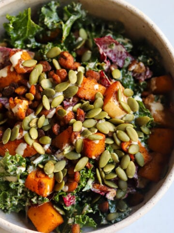 Overhead view of Autumn Harvest Salad in a bowl with toasted pepitas, roasted butternut squash, tempeh, kale and radichhio