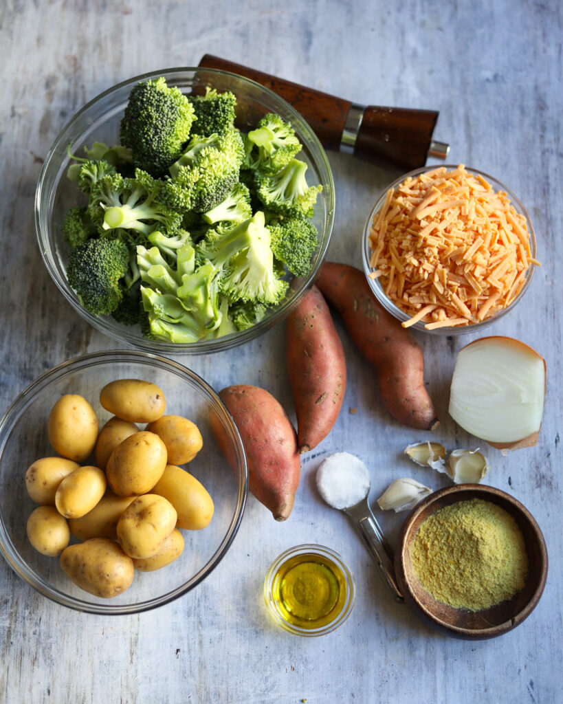 overhead view of Broccoli and Cheddar Soup ingredients. Broccoli, potatoes, sweet potatoes, garlic, onion, nutritional yeast