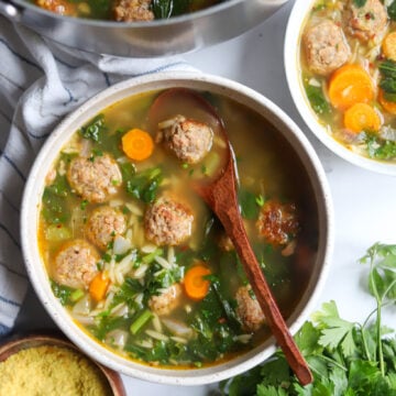 overhead view of vegan Italian Wedding Soup with meatballs, greens, herbs and carrots