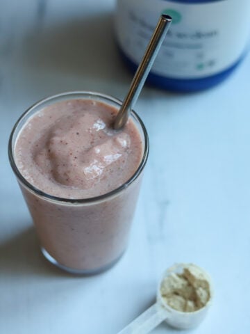 Looking down at a glass full of a light pink, thick and creamy High Protein Vegan Berry Vanilla Breakfast Smoothie