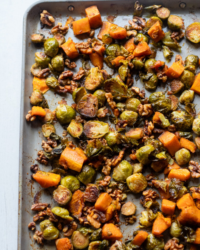 Overhead view of cooked brussels sprouts and squash on a sheet pan