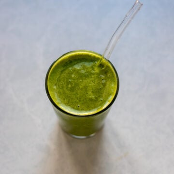 overhead view of healthy green smoothie in a glass with a straw
