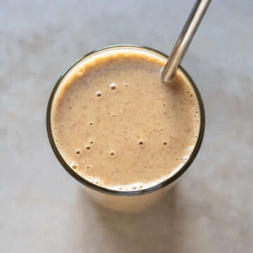 closeup overhead view of a smoothie in a glass with a metal straw
