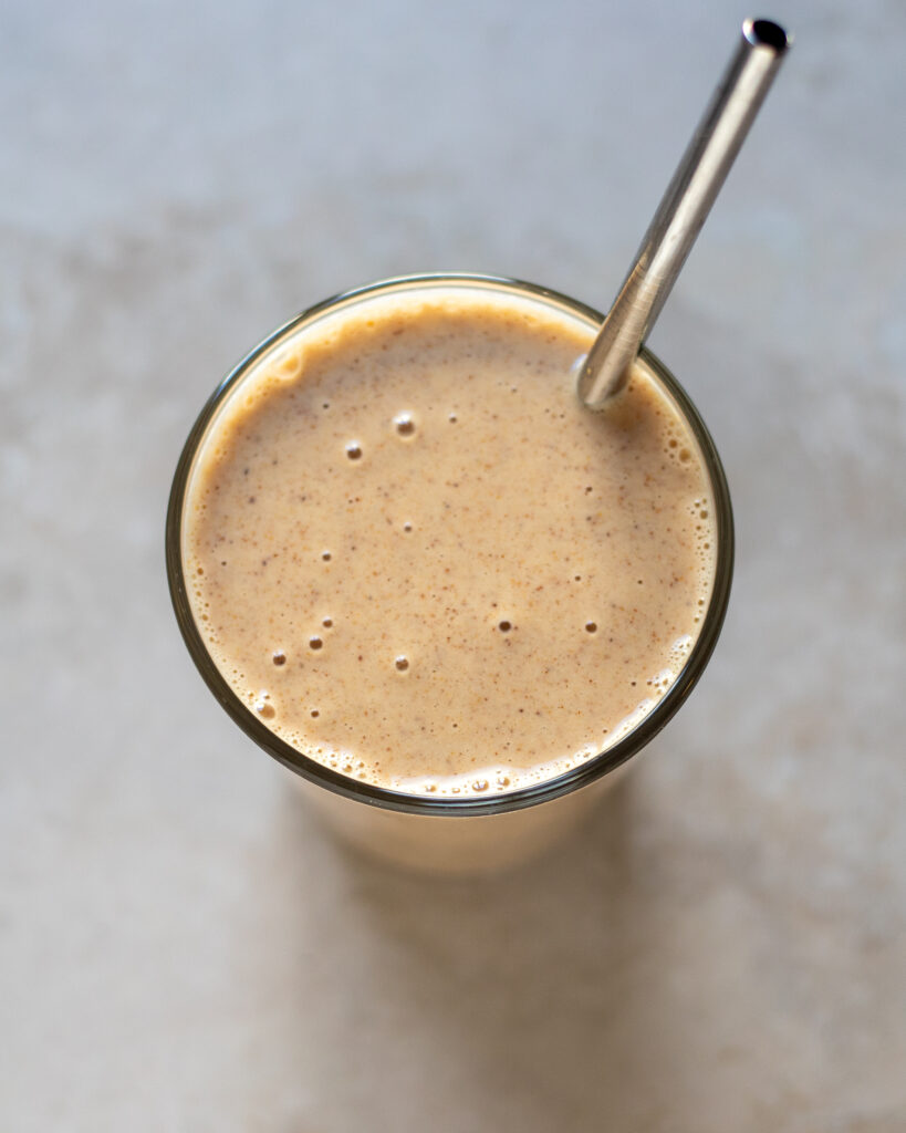 closeup overhead view of a smoothie in a glass with a metal straw