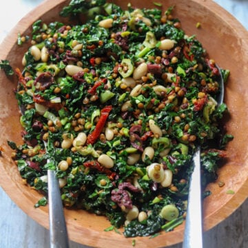close up of a salad with lentils, beans, olives and sun-dried tomatoes in a wood bowl