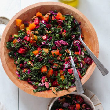 overhead view into colorful beet and kale salad in a wooden bowl with a serving utensil