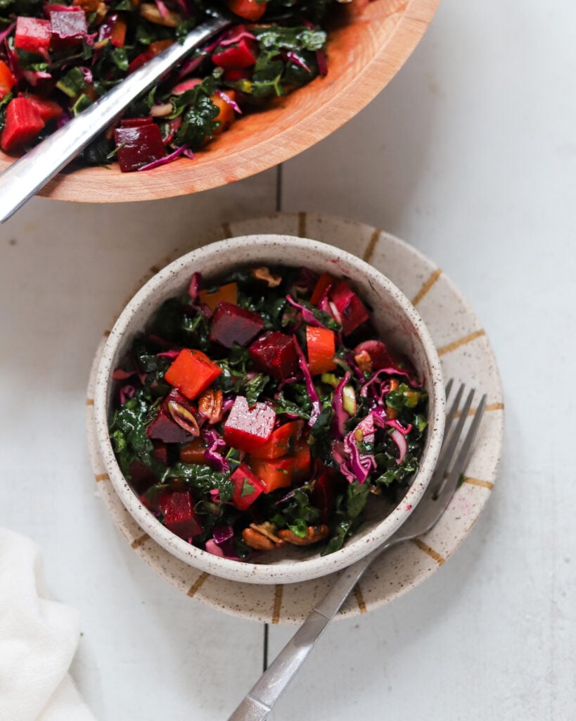 Close up overhead of a small bowl of kale beet salad with pecans and dill