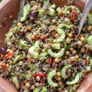 close up view of Mediterranean Wild Rice Salad with Chickpeas and Olives in a wood bowl with serving spoons