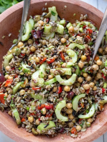 close up view of Mediterranean Wild Rice Salad with Chickpeas and Olives in a wood bowl with serving spoons