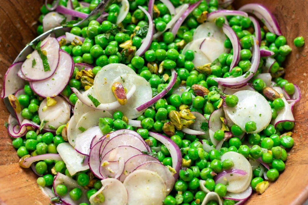 closeup of healthy pea salad with radishes, red onions, mint and pistachios