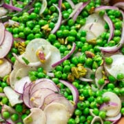 closeup of healthy pea salad with radishes, red onions, mint and pistachios