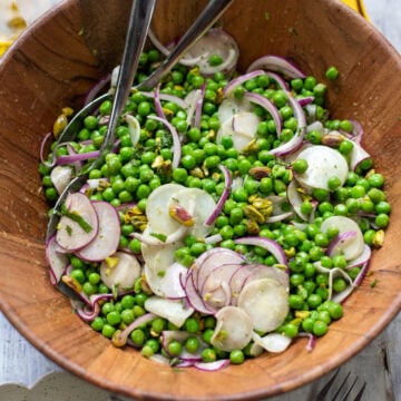 big wood bowl filled with healthy pea salad with radishes, red onions, mint and pistachios