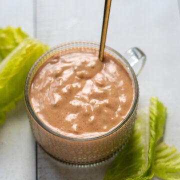 A small cup of Russian dressing surrounded by crispy lettuce