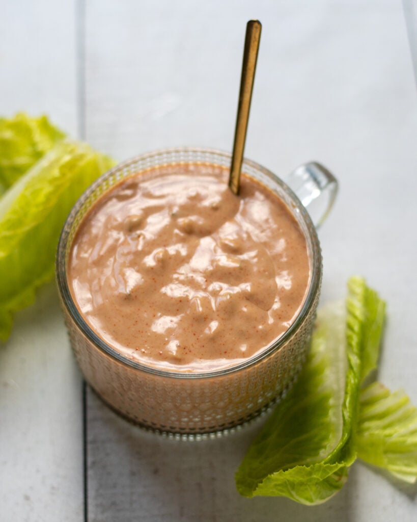 A small cup of Russian dressing surrounded by crispy lettuce