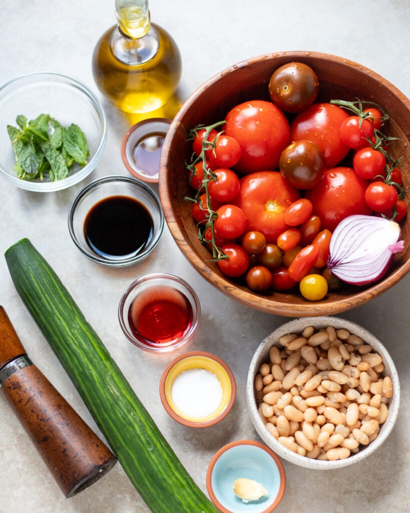 Ingredients for summer tomato salad laid out in small bowls