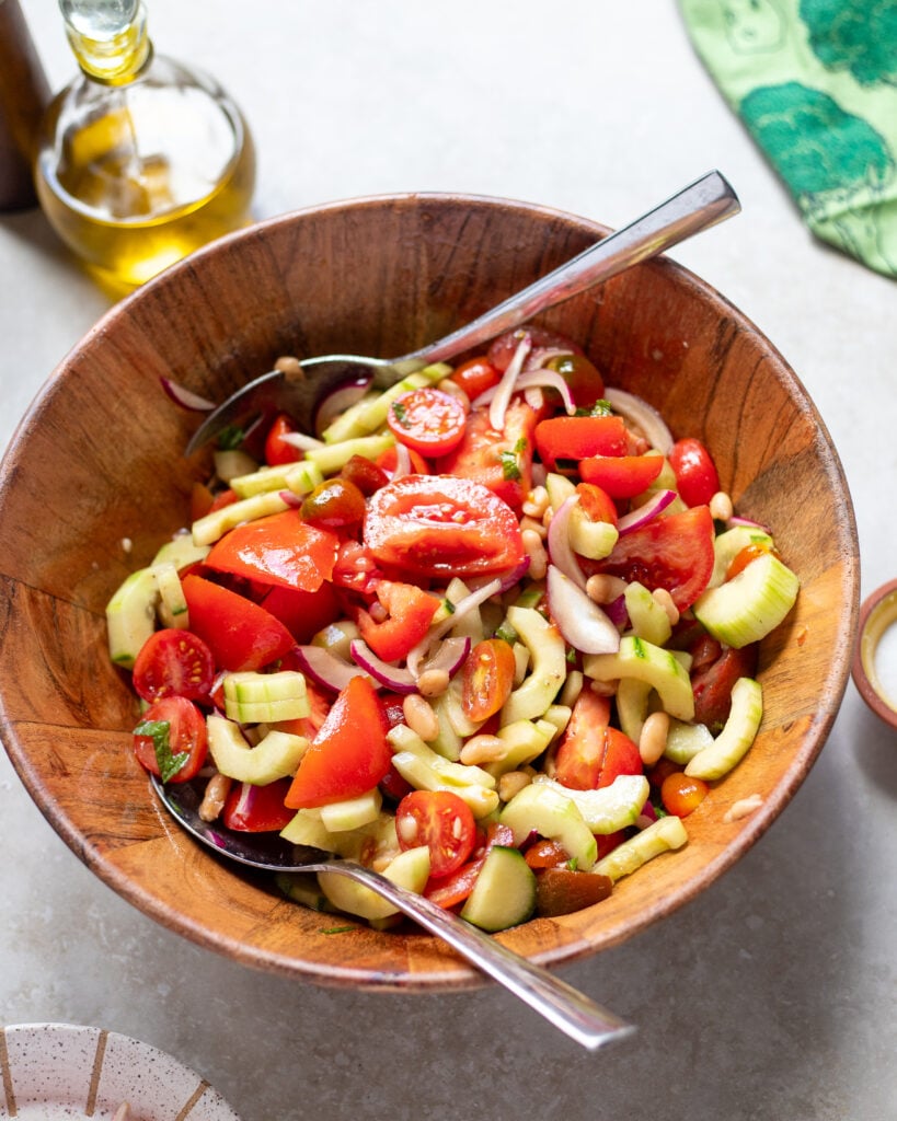 looking into a bowl of summer tomato salad with cucumbers, herbs and onions