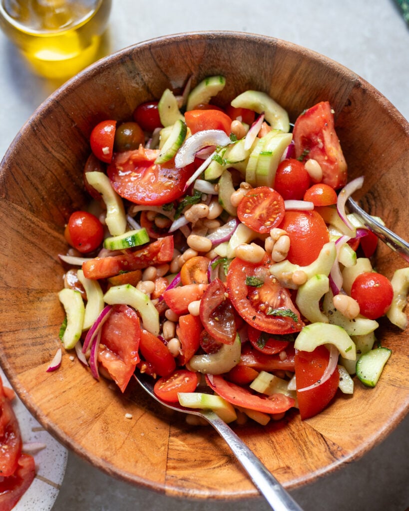 looking closer into a bowl of summer tomato salad with cucumbers, herbs and onions